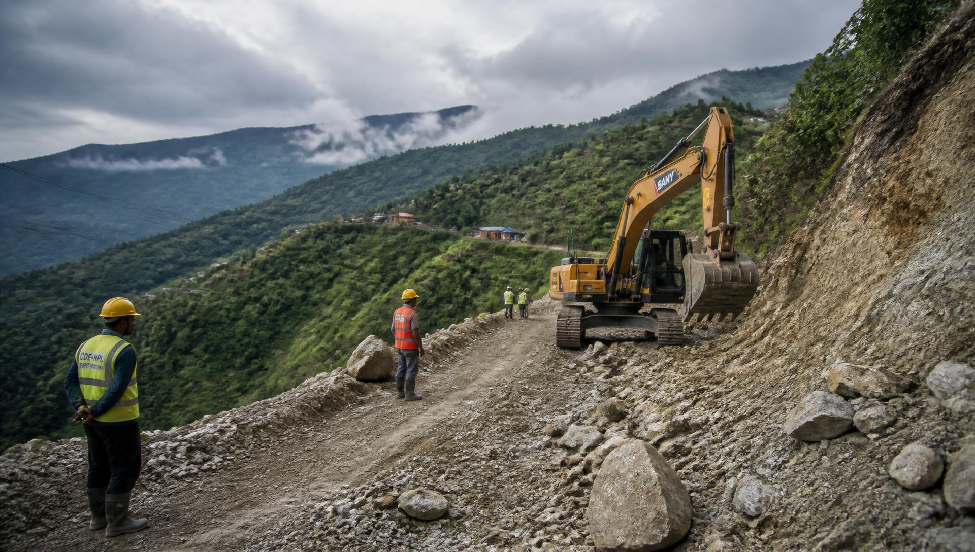 Excavator cutting a hill road during construction in eastern Nepal